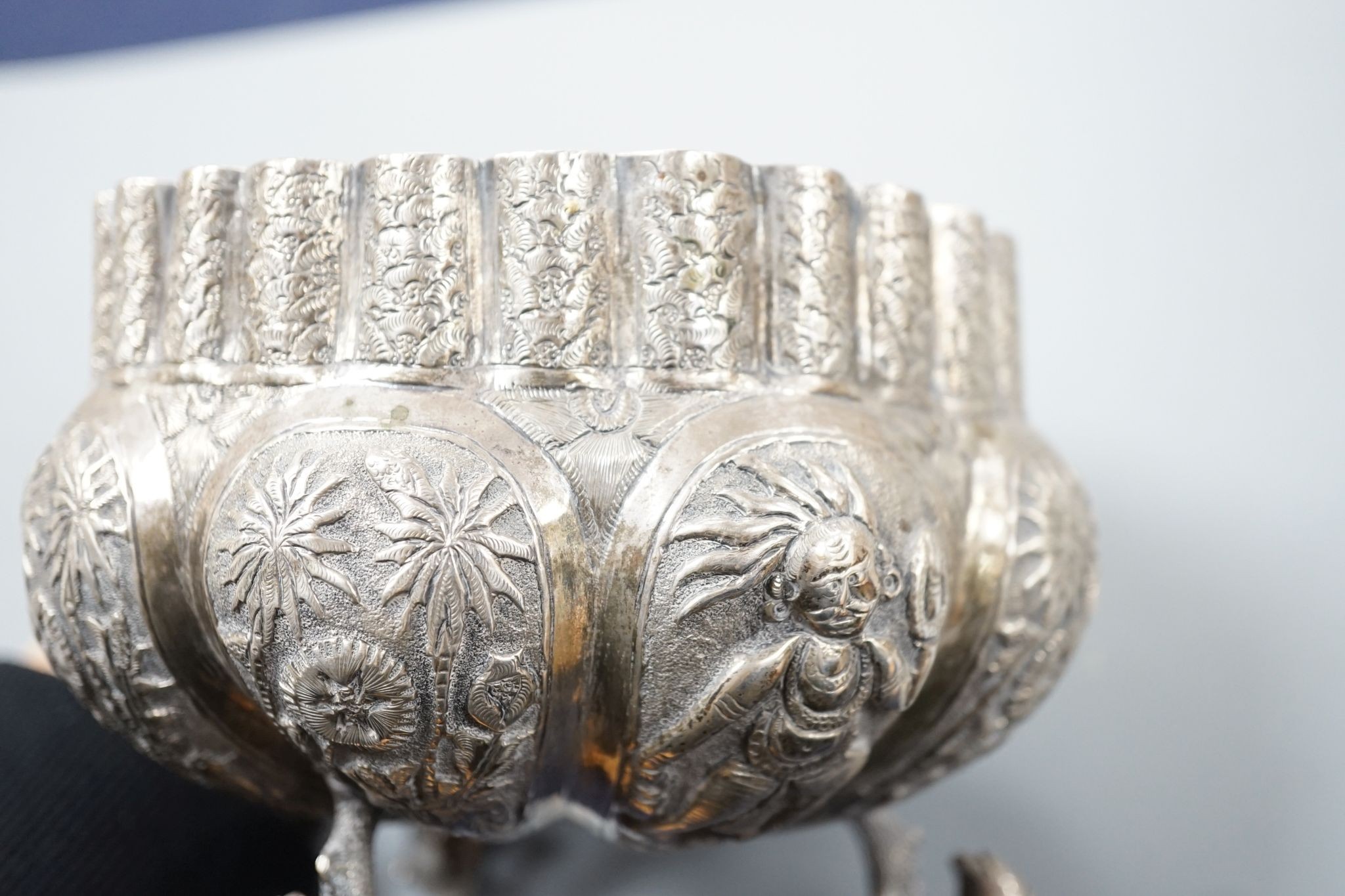 An Indian embossed white metal bowl, on three dolphin feet, diameter 13cm, 10oz.